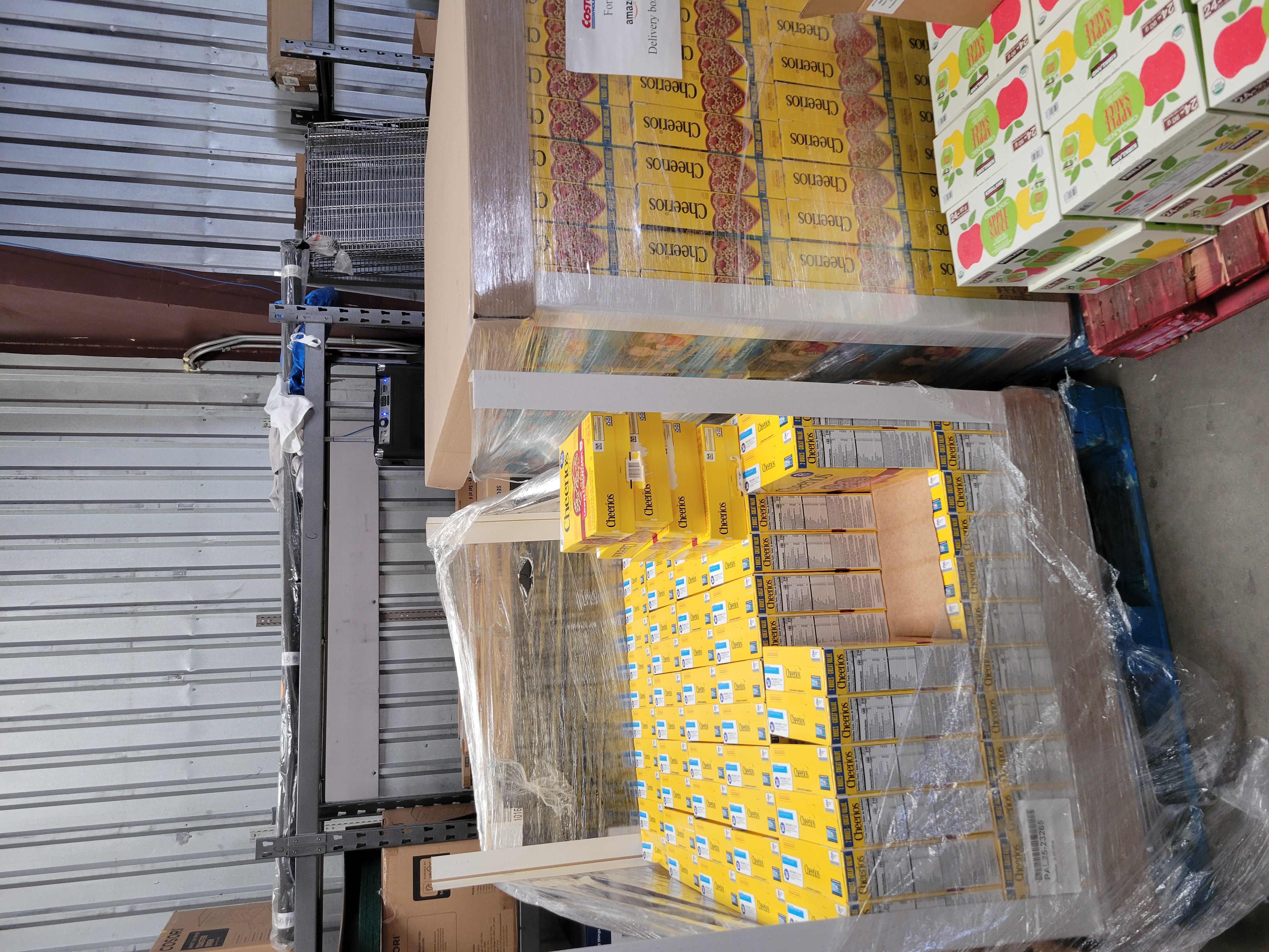 Pallets of boxes of Cheerios with pallet of boxes of apple sauce in front of it.